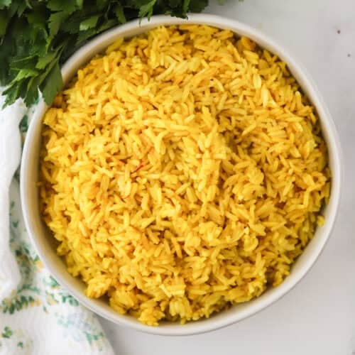 How to make yellow rice, saffron rice recipe. Yellow rice in a white bowl, overhead short.