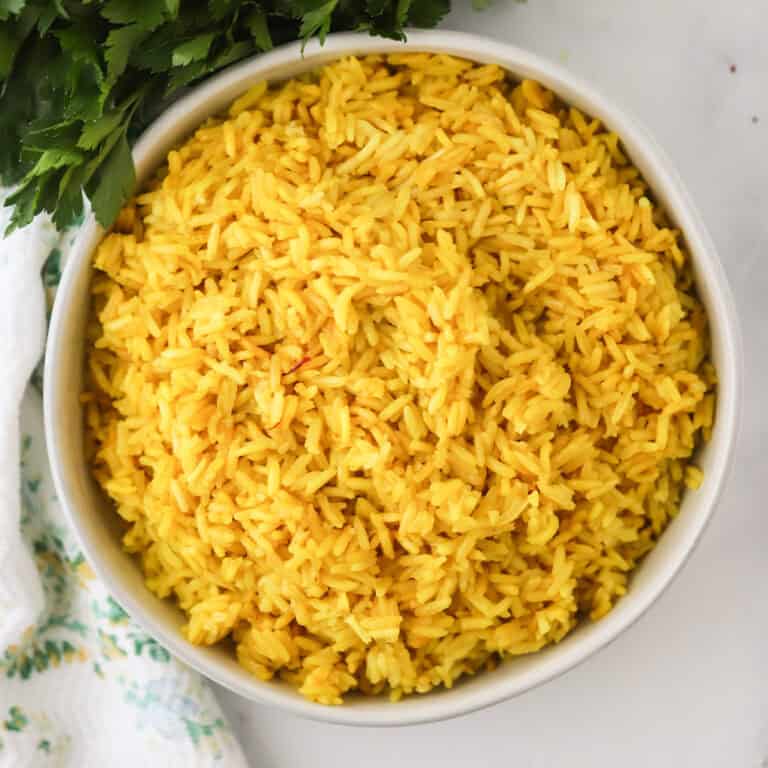 How to make yellow rice, saffron rice recipe. Yellow rice in a white bowl, overhead short.
