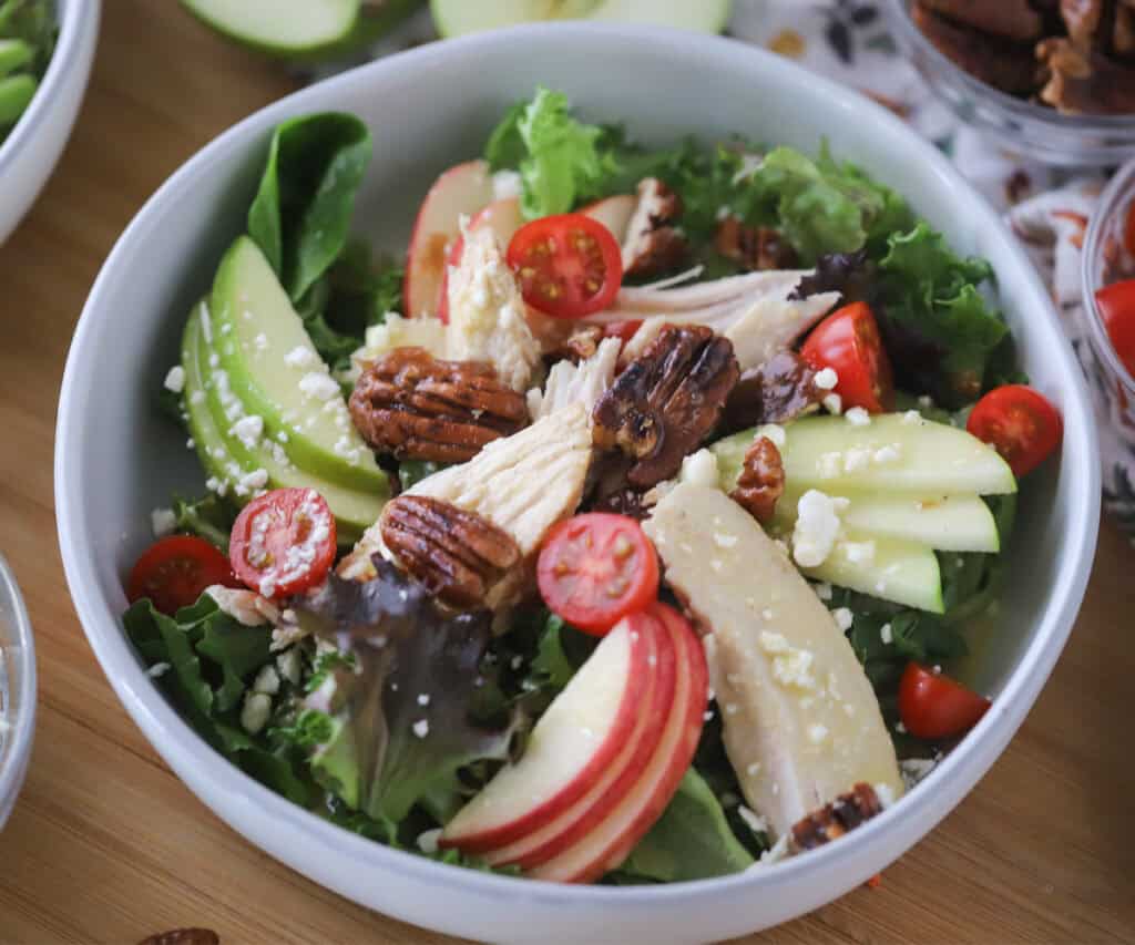 A serving bowl with rotisserie chicken salad covered in honey mustard dressing.