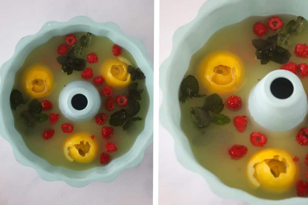 Lemonade poured over the bottom of a bundt cake pan filled with lemon rosettes, raspberries, and mint leaves.