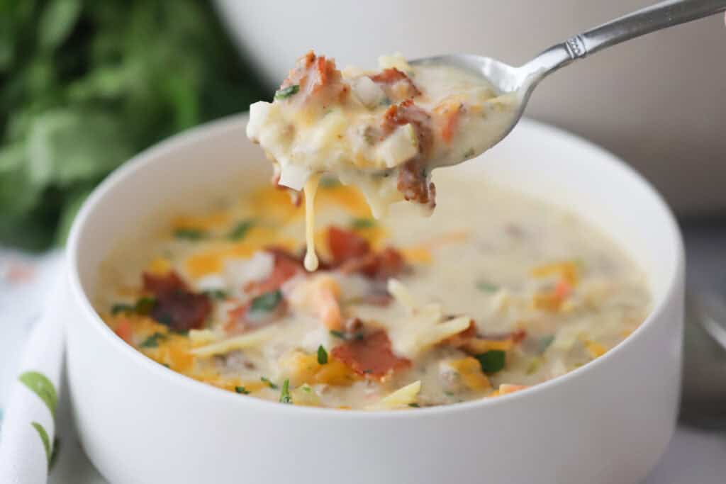 A spoon with a bowl of cheeseburger soup.