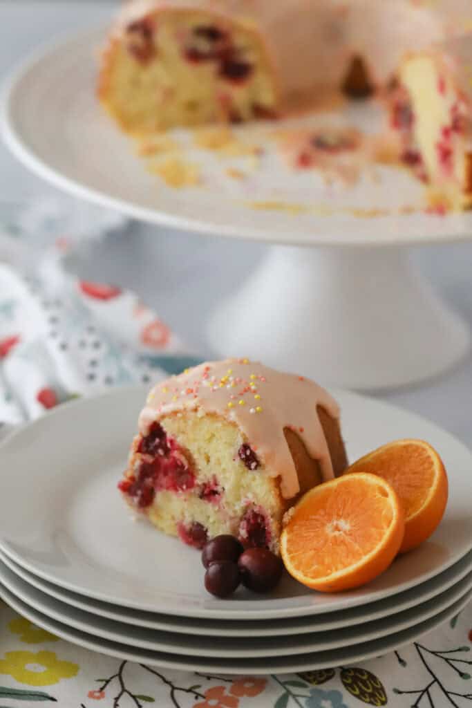 A stack of white dessert plates with a slice of cranberry cake.