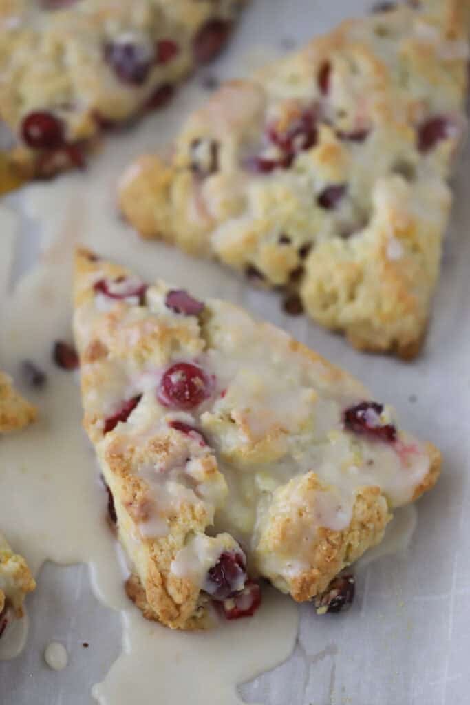 Cranberry orange cream scones cut into triangles and topped with orange glaze.