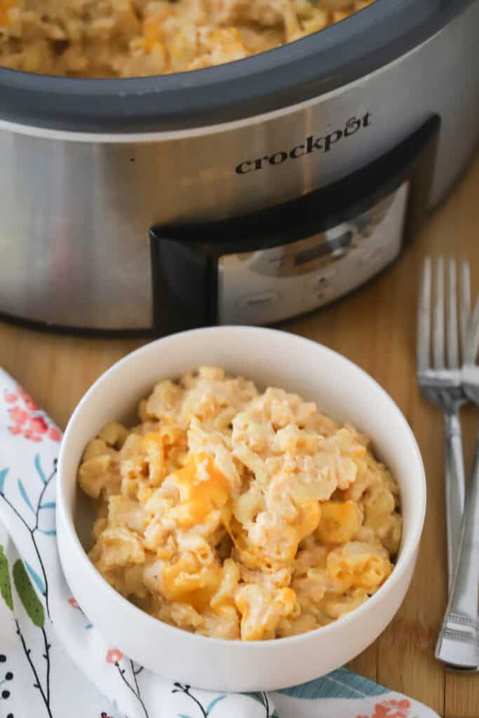 A bowl of the best slow cooker mac and cheese on a table with a slow cooker in the background.