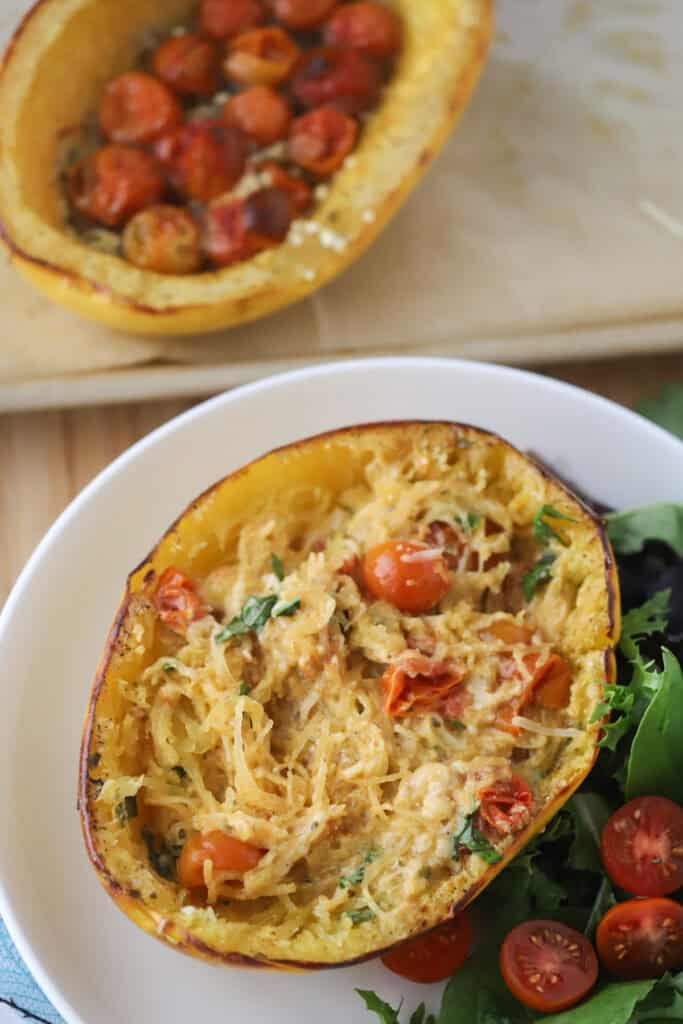 A plate with baked spaghetti squash with tomatoes and feta.