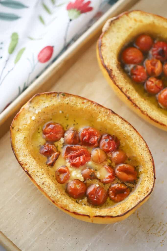 Half of a roasted spaghetti squash with tomatoes and feta.