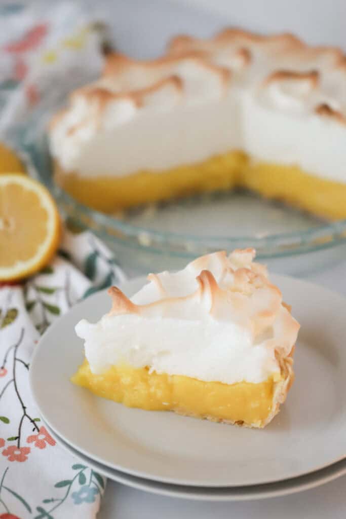 A white plate with a slice of lemon meringue pie.