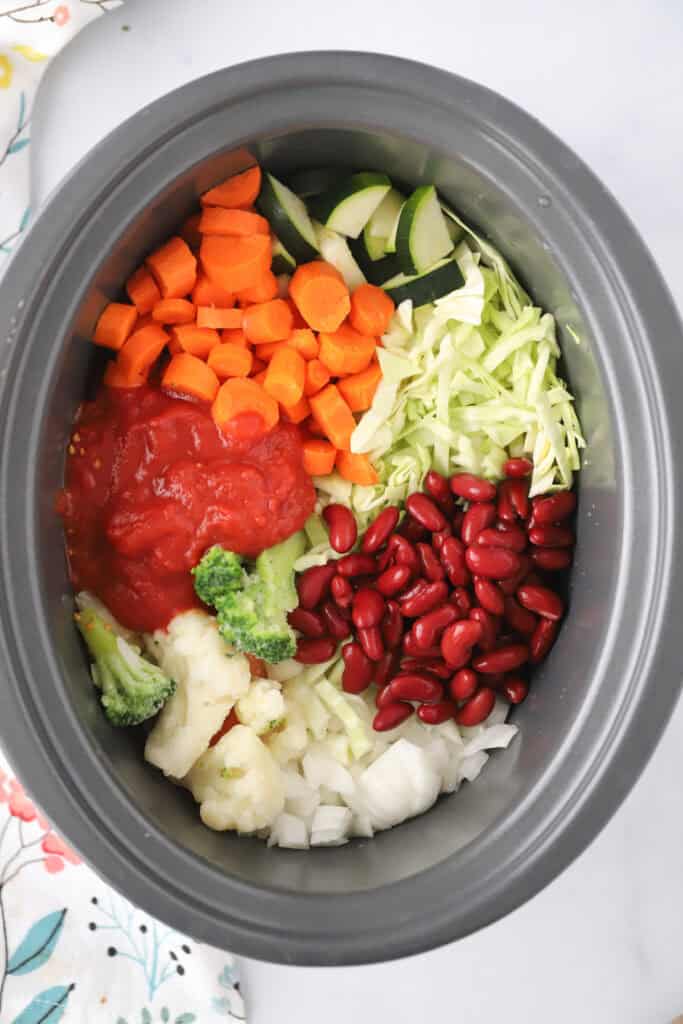 A crockpot full of the ingredients needed to make this slow cooker minestrone soup recipe.