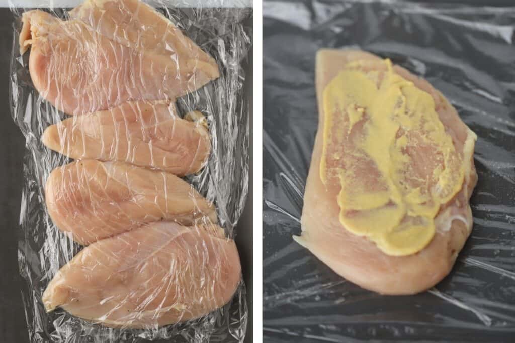 Raw chicken breasts being pounded between two pieces of plastic wrap, topped with Dijon mustard.