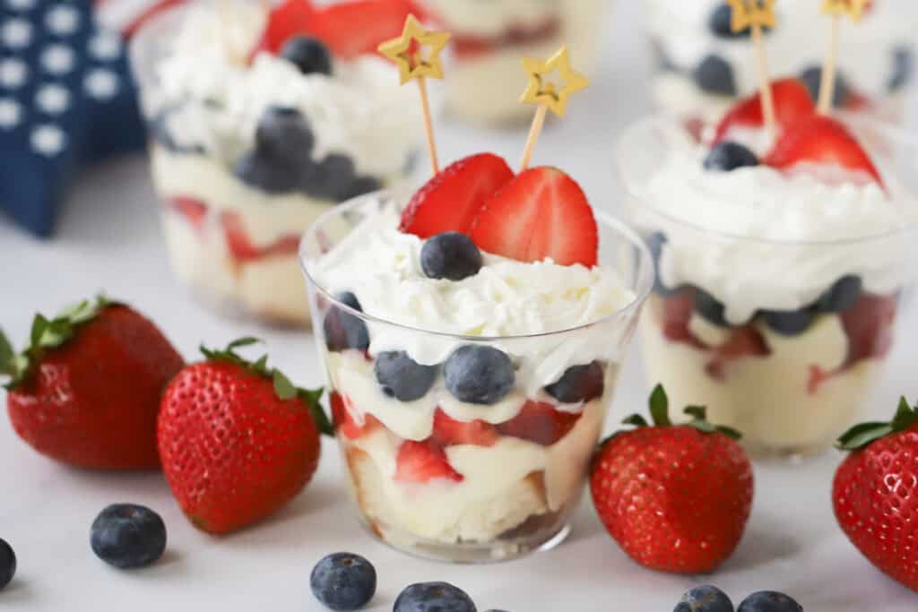 Berry trifle desserts inside plastic cups decorated for the 4th of july.