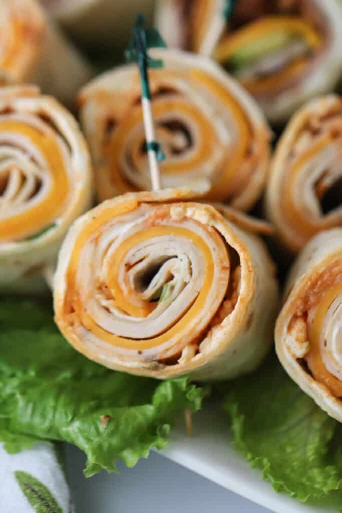 A platter with small buffalo chicken pinwheels with toothpicks for serving.