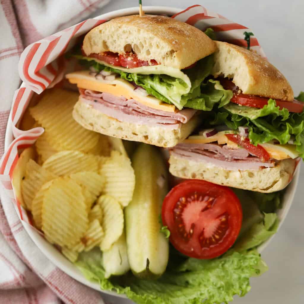 A plate with a couple of Italian club sandwiches sliced so you can see the meats, cheeses, and veggies inside.