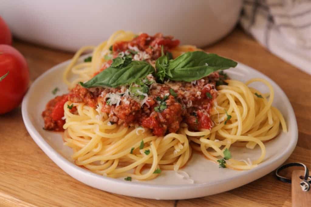 A plate of spaghetti topped with homemade meat sauce and fresh basil.