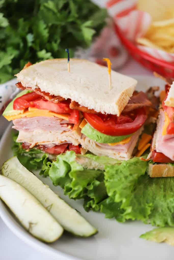 A turkey club sandwich on a plate with toothpicks stuck in the middle.